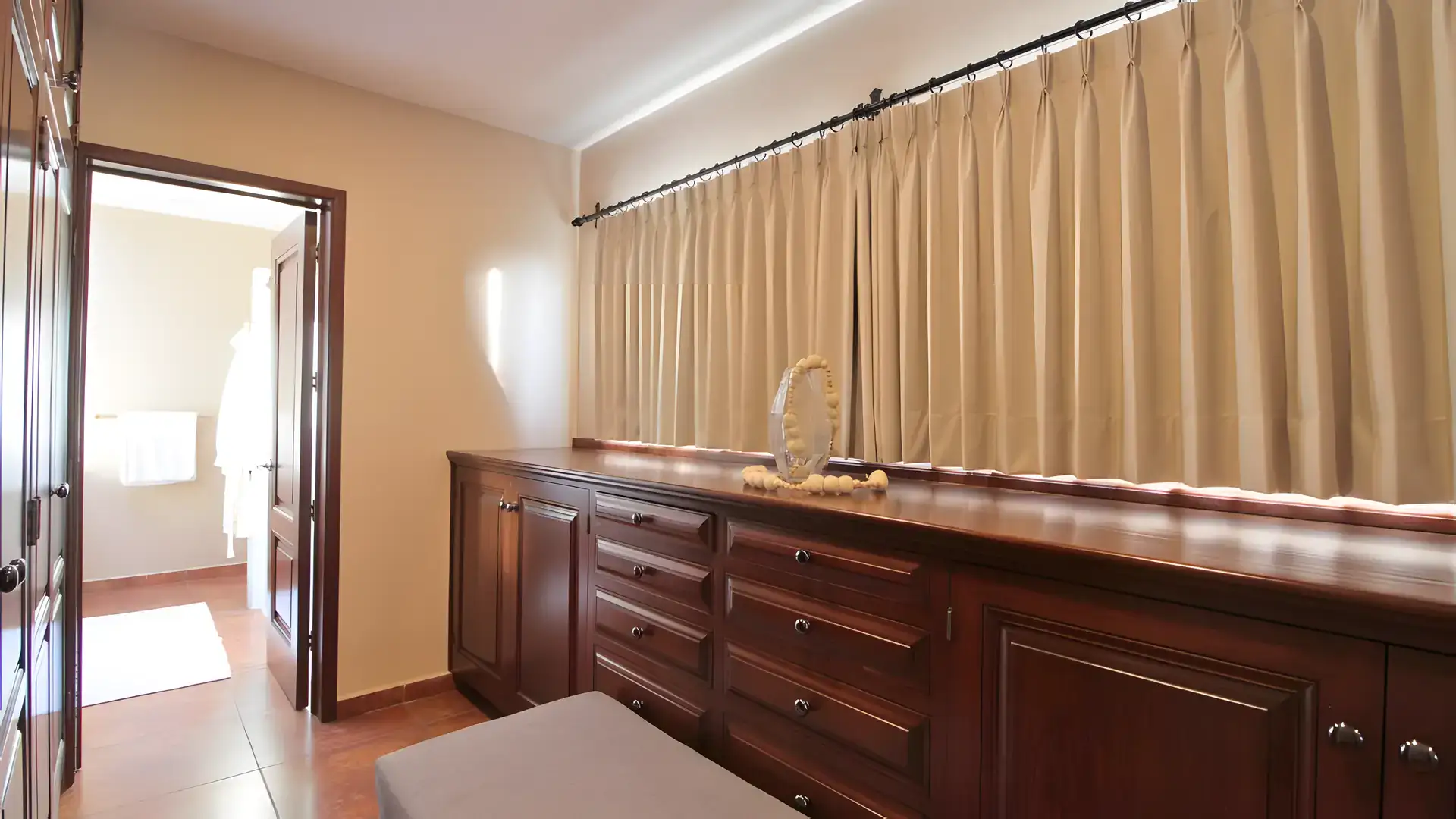 Casa Bellavista, sitting room with a wood sideboard, tan curtains and a view into a bathroom, San Miguel de Allende