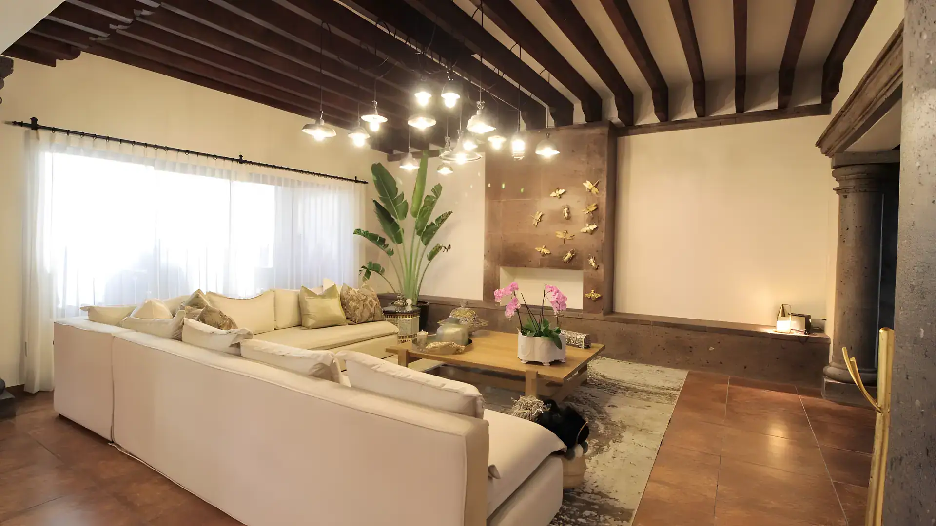Casa Bellavista, living room with a cream sectional, a hanging light fixture and a stone column, San Miguel de Allende