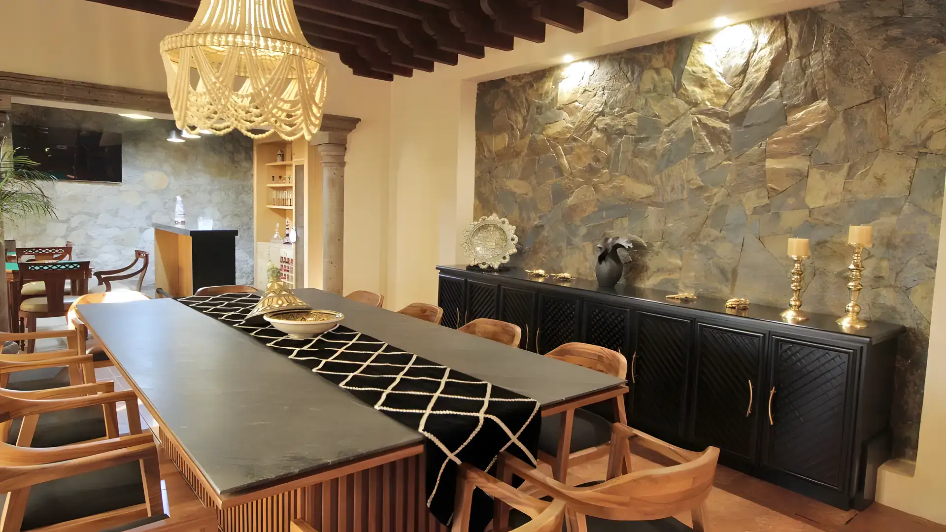 Casa Bellavista, dining table with a black and white runner and a stone wall with a television, San Miguel de Allende