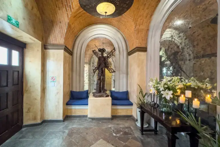 Casa Biblioteca, entry foyer with a brick vaulted ceiling, a winged sculpture in an arched niche and candles on a console, San Miguel de Allende