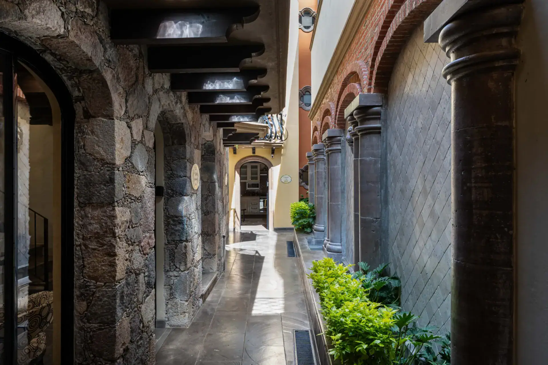 Casa Biblioteca, narrow stone passage between the units with a beamed overhang and planters, San Miguel de Allende