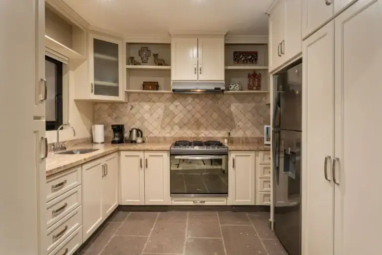 Casa Biblioteca, kitchen with cream cabinets, tile backsplash, a gas range and a stainless refrigerator, San Miguel de Allende