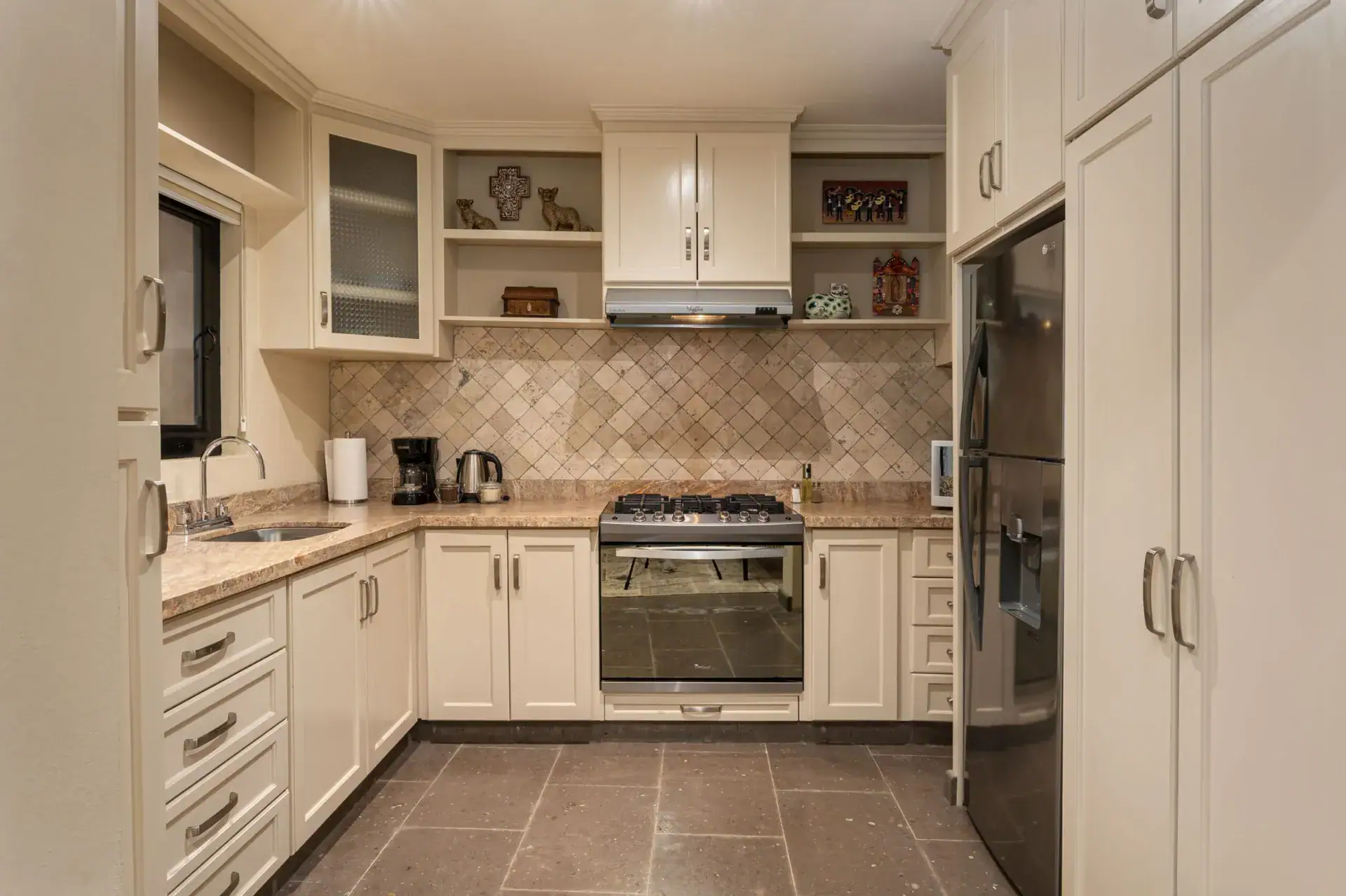 Casa Biblioteca, kitchen with cream cabinets, tile backsplash, a gas range and a stainless refrigerator, San Miguel de Allende