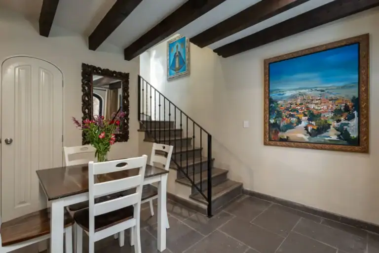 Casa Biblioteca, dining table beside a staircase and a large blue landscape painting, San Miguel de Allende
