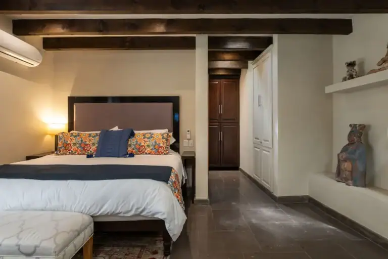 Casa Biblioteca, bedroom with a dark headboard, floral bedding and built-in closets, San Miguel de Allende
