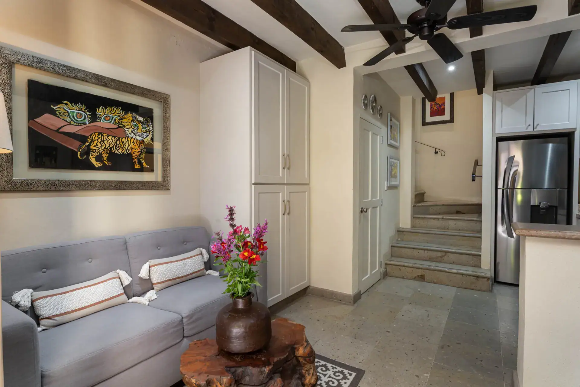 Casa Biblioteca, living area with a gray sofa, tiger artwork and a staircase to the kitchen, San Miguel de Allende