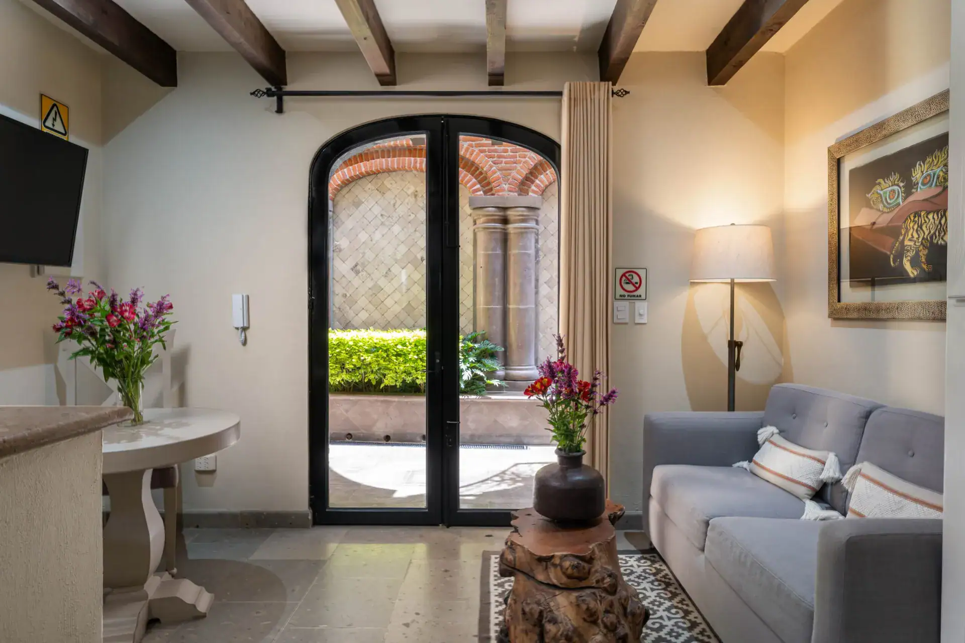 Casa Biblioteca, sitting room with an arched glass door, gray sofa and wall art, San Miguel de Allende