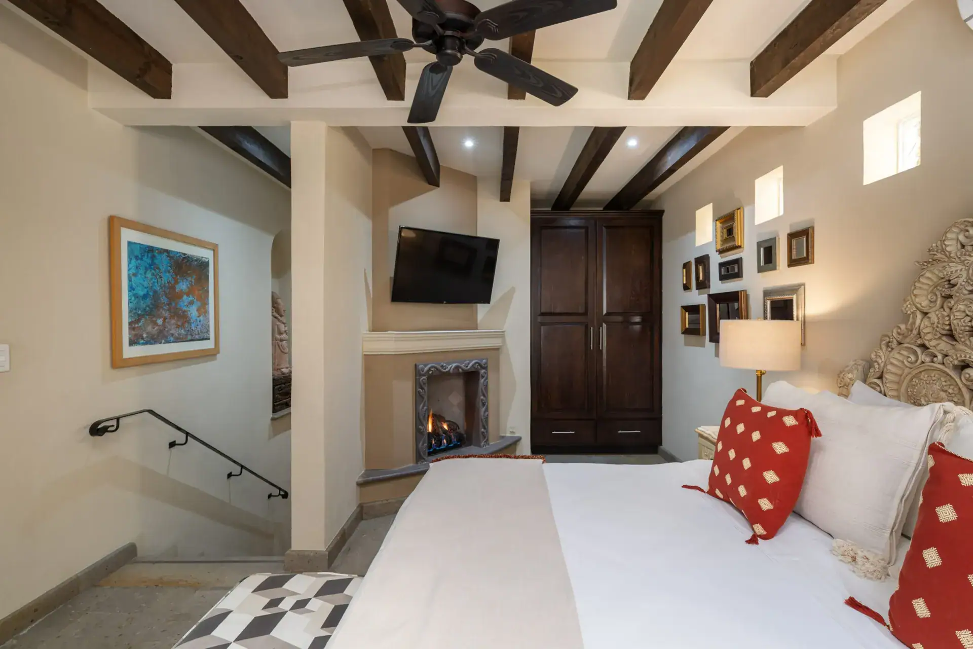 Casa Biblioteca, bedroom with a fireplace, framed pictures and a carved headboard, San Miguel de Allende