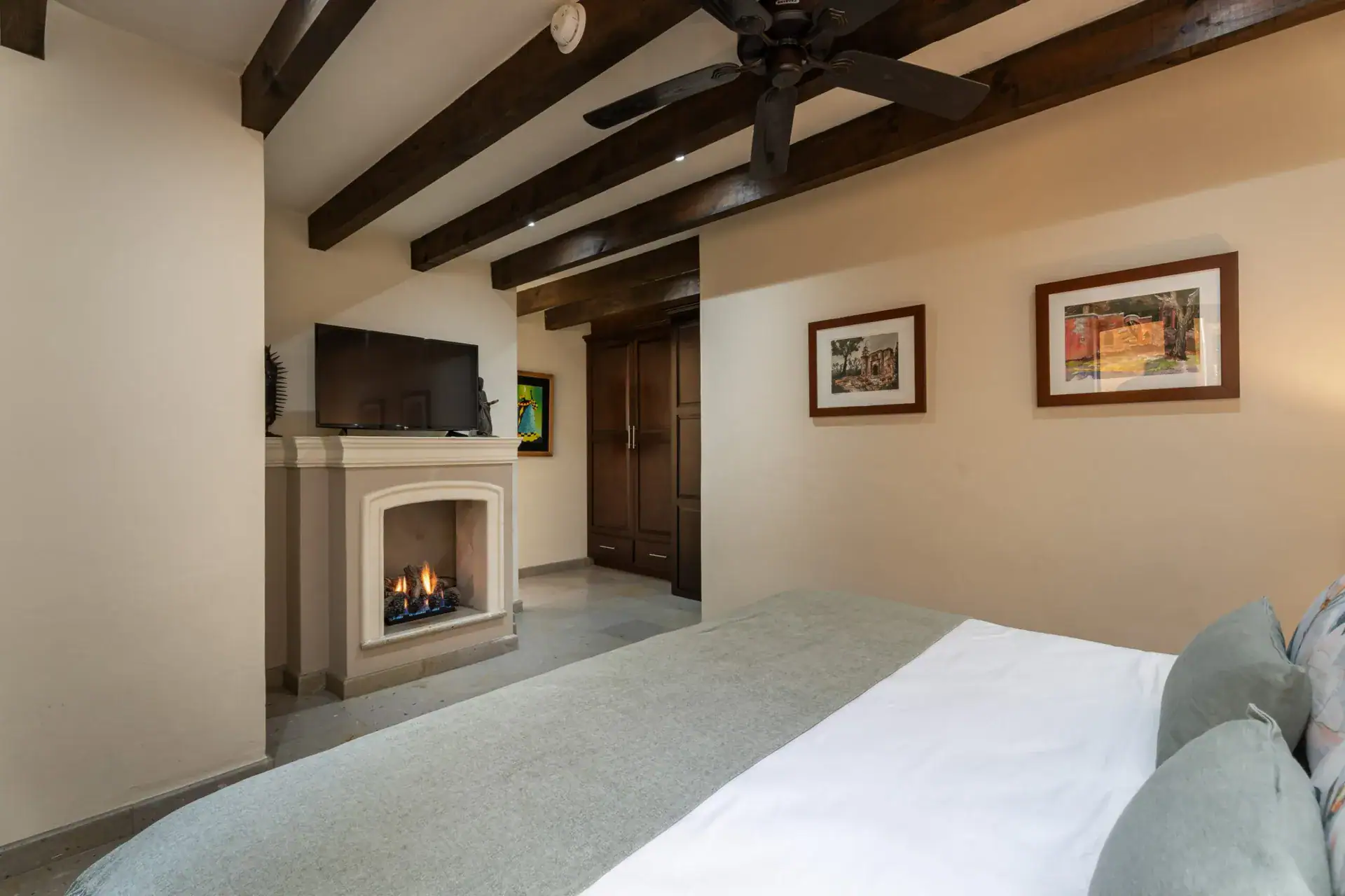 Casa Biblioteca, bedroom with a gas fireplace, television and a pale green bedspread, San Miguel de Allende