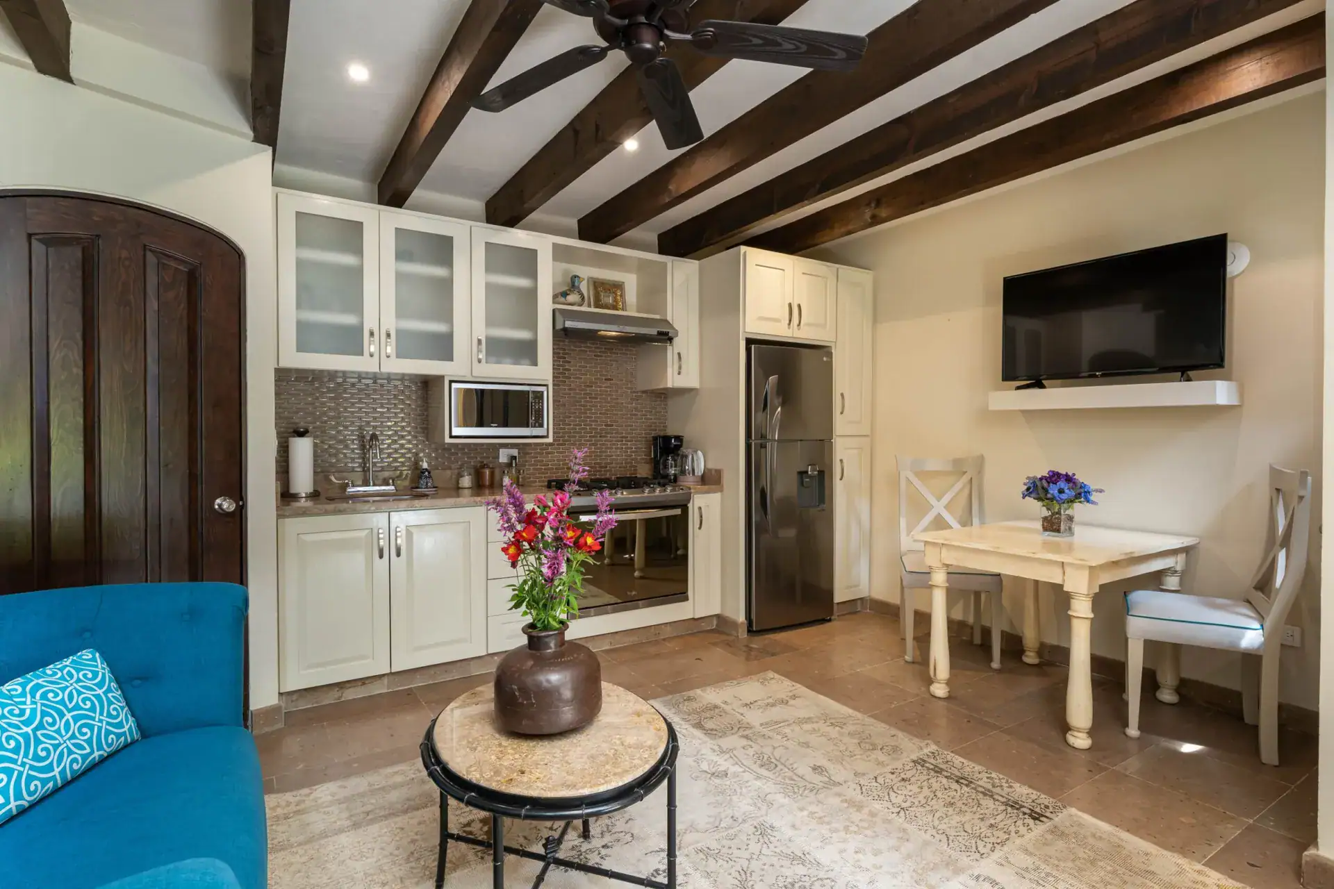 Casa Biblioteca, kitchenette with white cabinets, a stainless refrigerator and a blue sofa, San Miguel de Allende