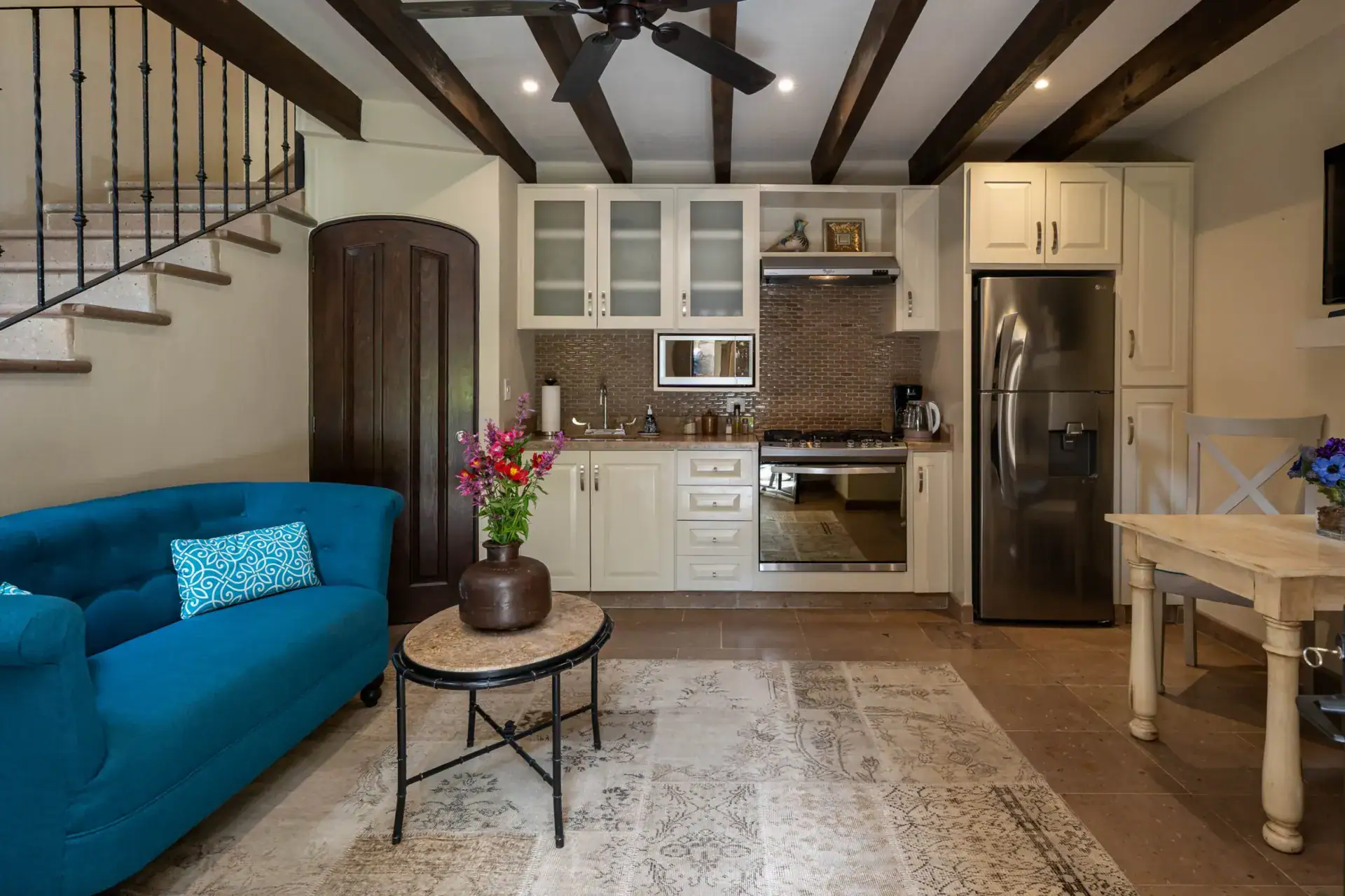 Casa Biblioteca, living area with a blue tufted sofa, kitchenette and a wrought-iron staircase, San Miguel de Allende