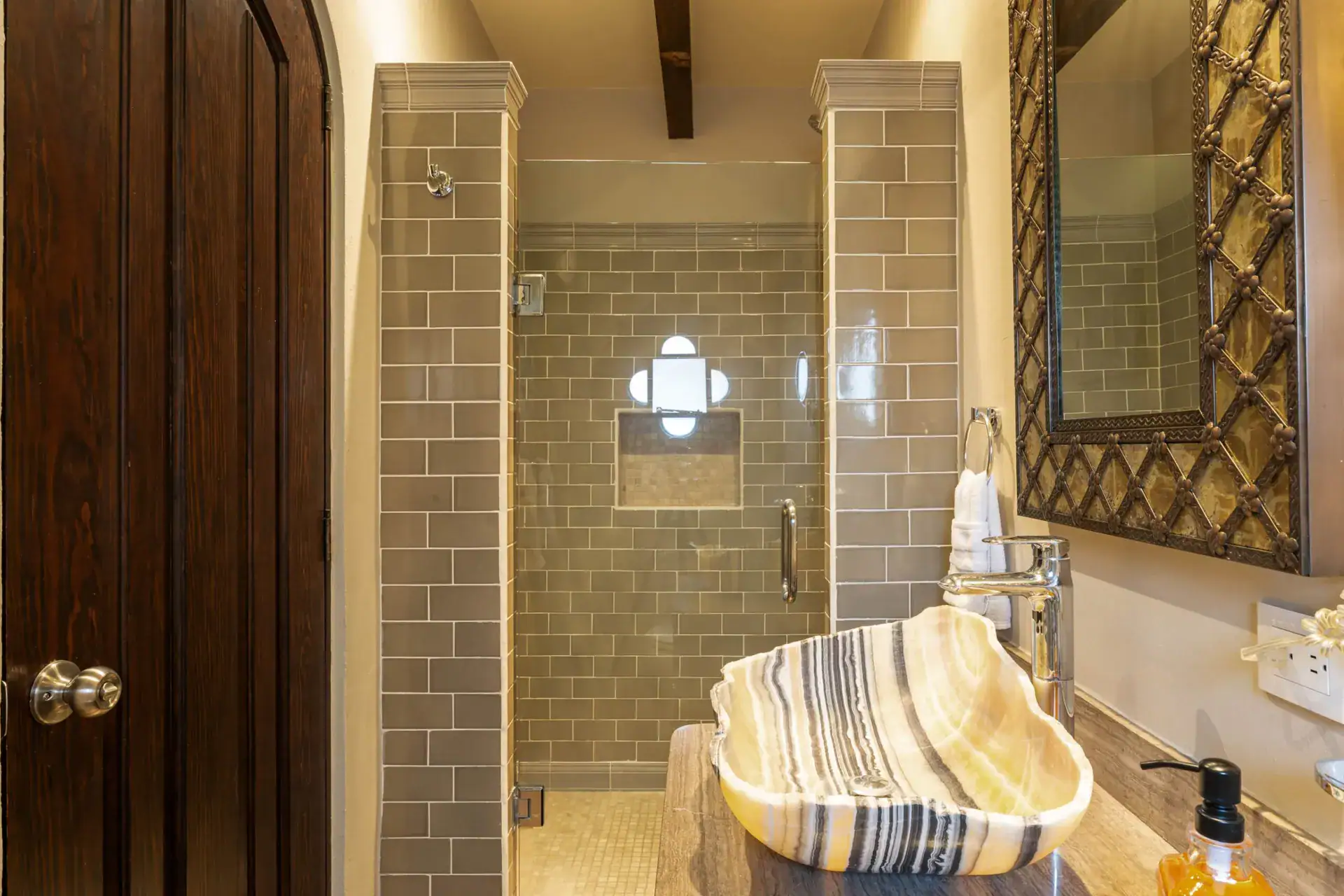 Casa Biblioteca, bathroom with a striped onyx vessel sink and a tiled glass shower, San Miguel de Allende