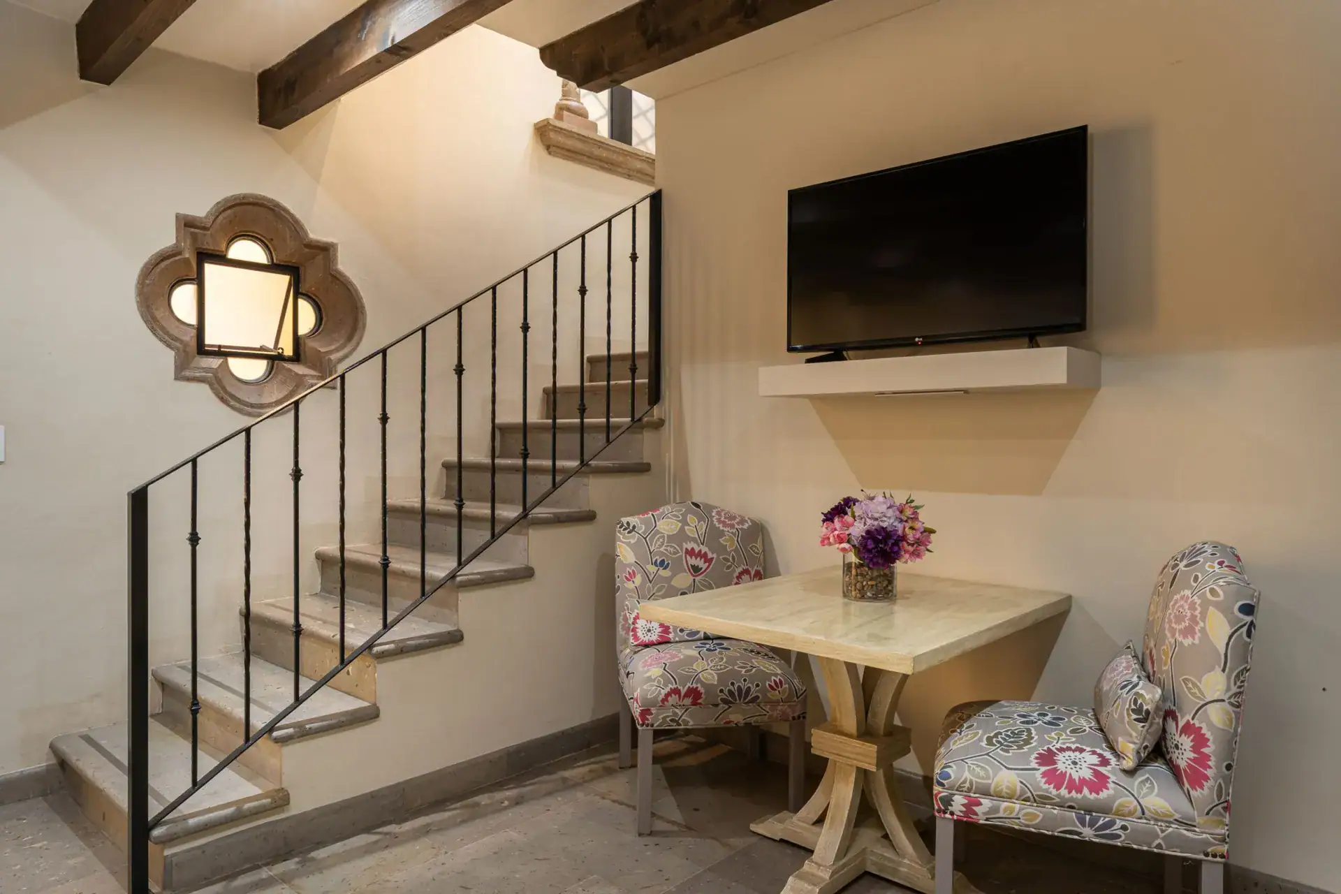 Casa Biblioteca, stairway landing with a television and a small table with floral chairs, San Miguel de Allende