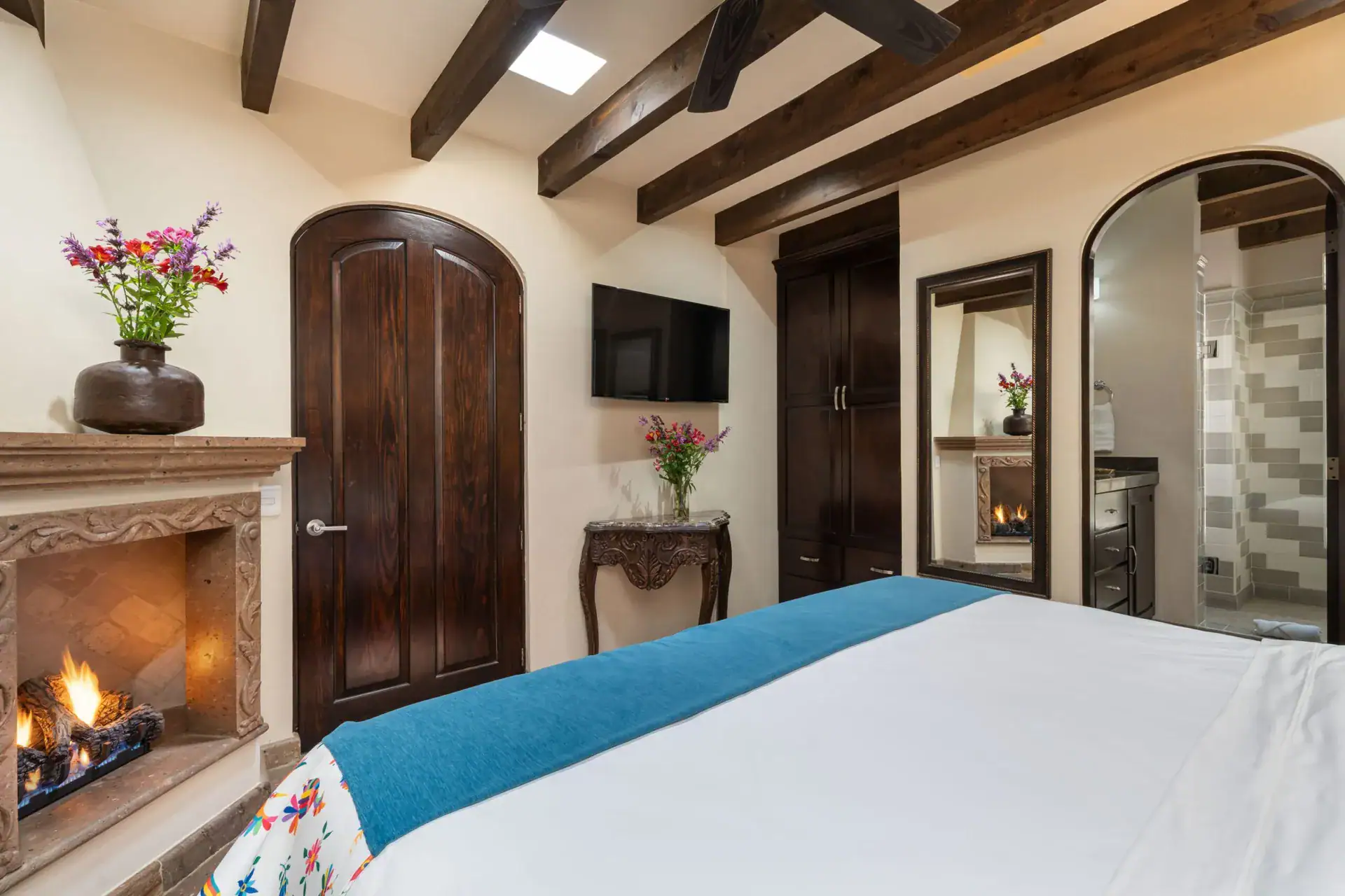 Casa Biblioteca, bedroom with a gas fireplace, tile accents and a teal bed runner, San Miguel de Allende