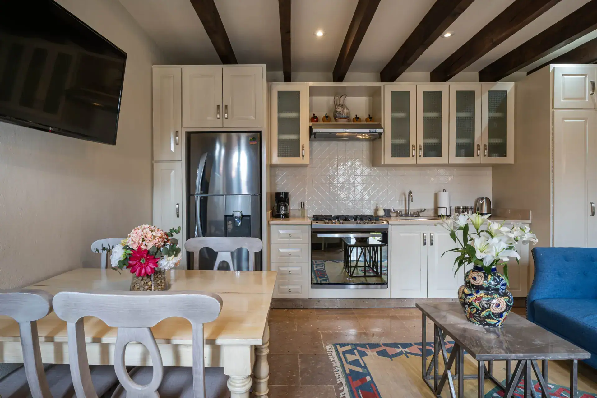 Casa Biblioteca, kitchen and dining area with a white table, stainless refrigerator and a television, San Miguel de Allende