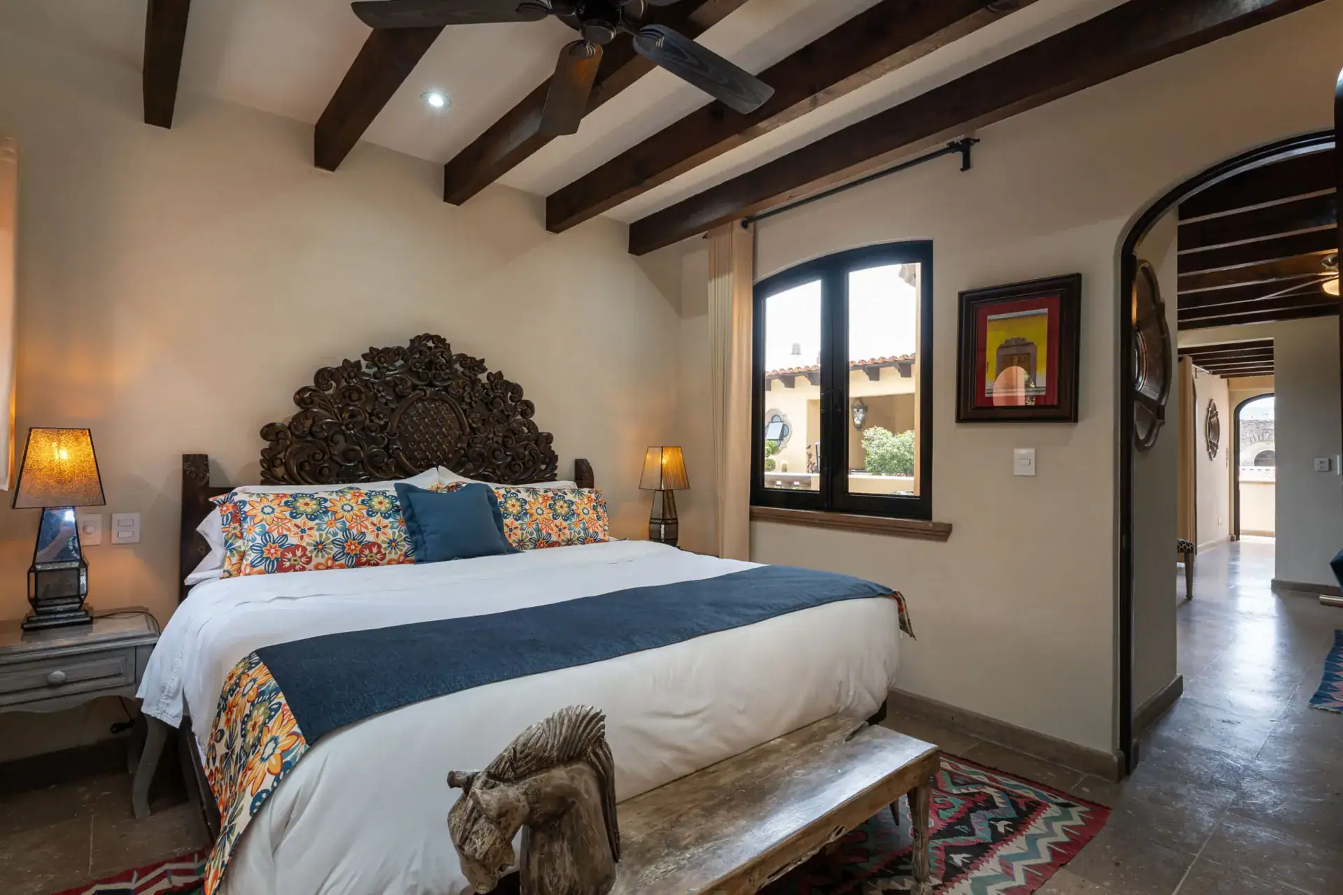 Casa Biblioteca, bedroom with a carved headboard, navy runner and arched windows, San Miguel de Allende