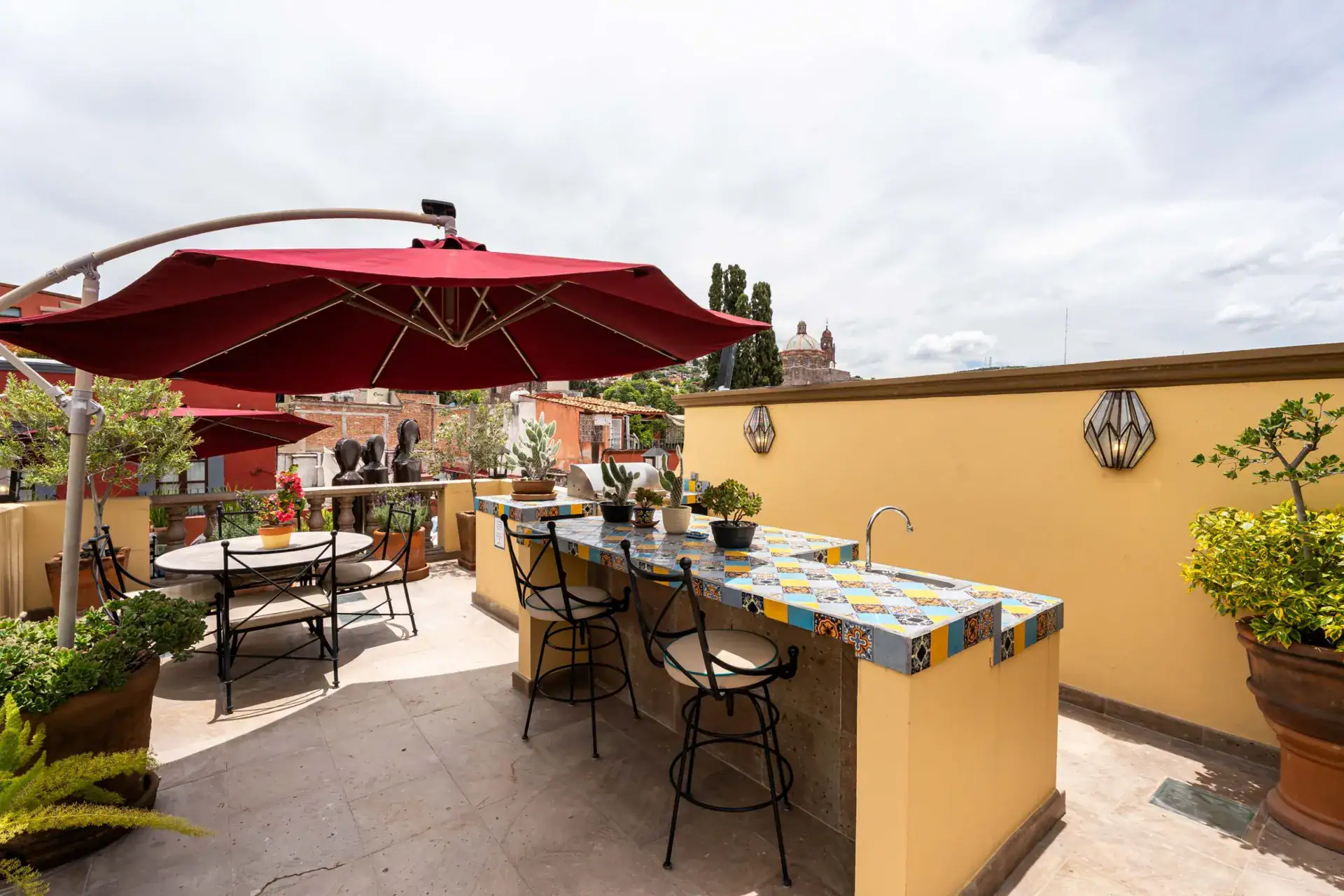 Casa Biblioteca, rooftop terrace with a red umbrella, tiled outdoor bar with stools and a view of the town, San Miguel de Allende