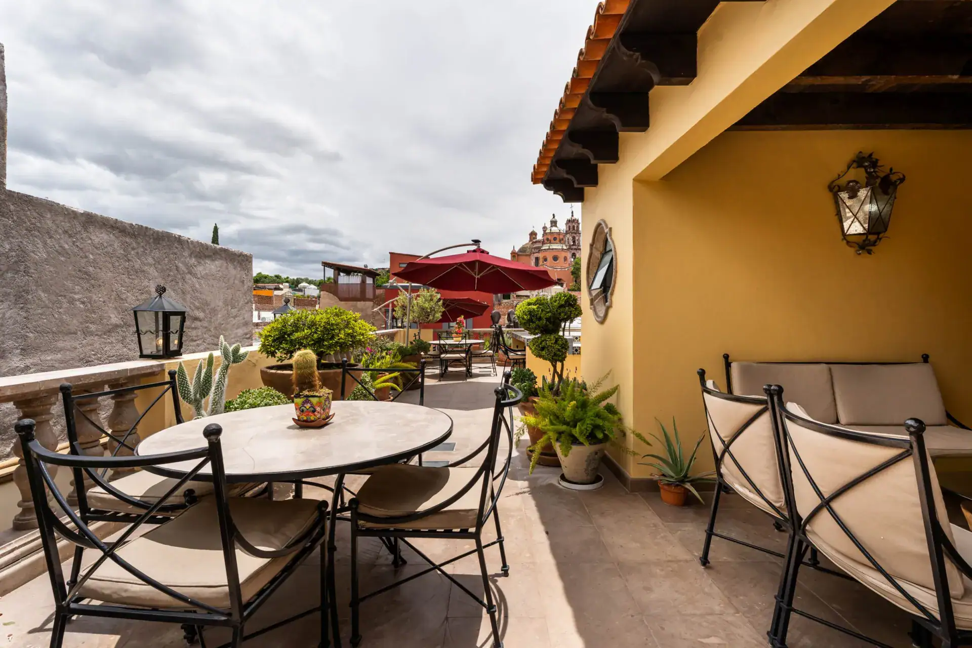 Casa Biblioteca, rooftop terrace dining table and a covered seating nook with a view to the church dome, San Miguel de Allende