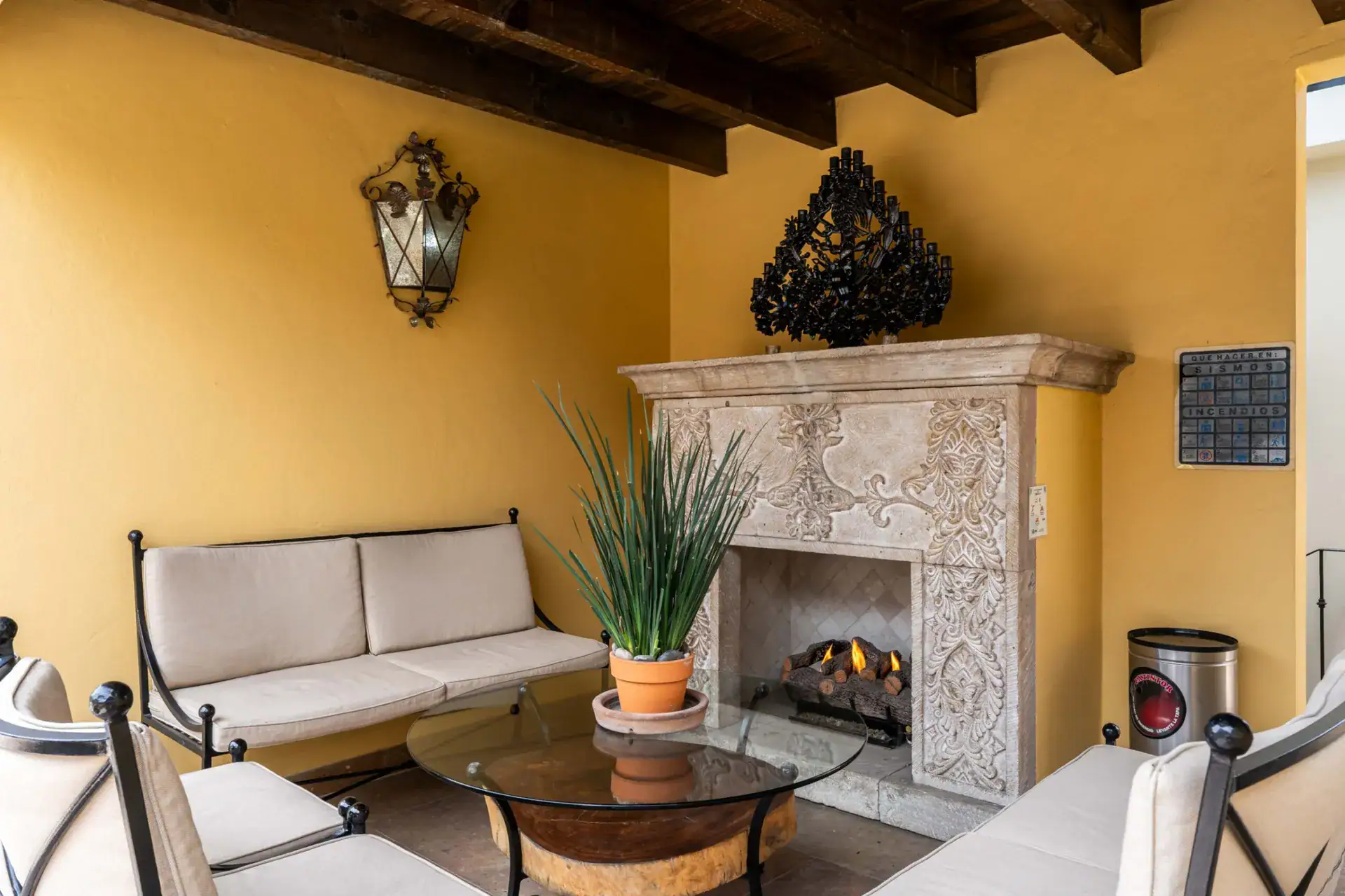 Casa Biblioteca, covered terrace sitting area with a stone fireplace, sofas and a wall lantern, San Miguel de Allende