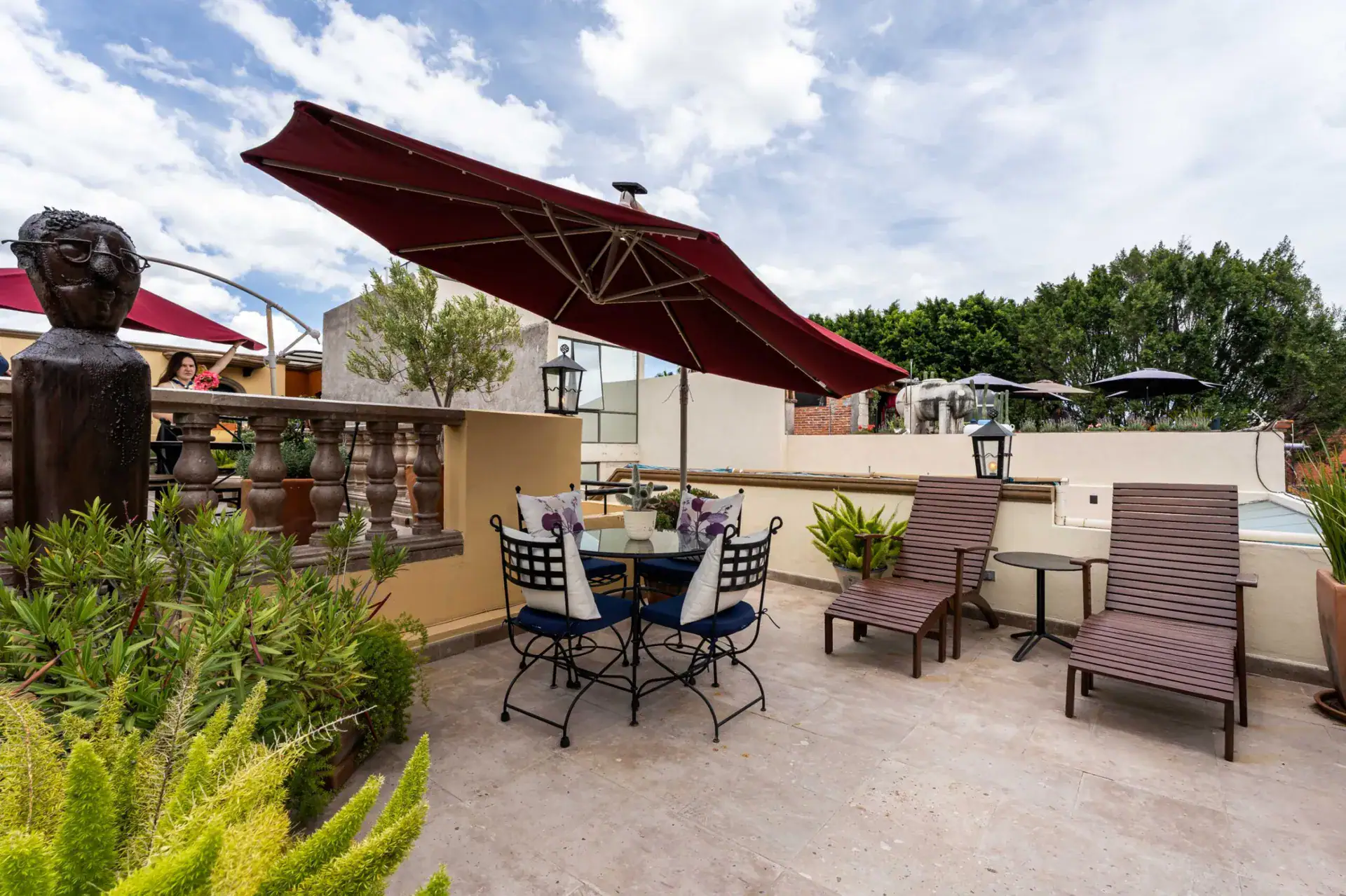 Casa Biblioteca, rooftop terrace with lounge chairs, a dining table and carved wooden figures, San Miguel de Allende