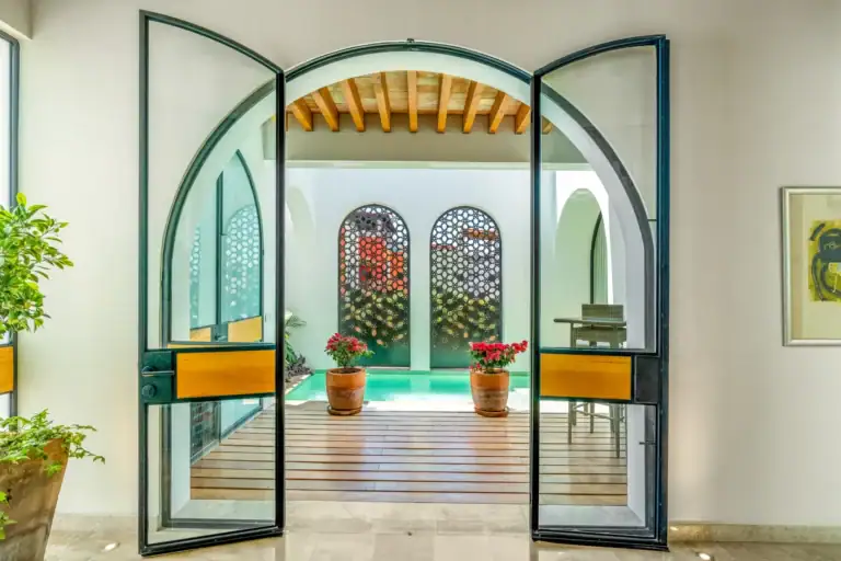 Casa Buenos Tiempos, arched steel and glass doors opening to a courtyard with a turquoise plunge pool, San Miguel de Allende