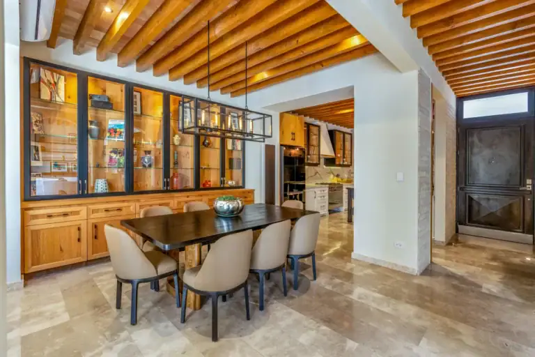Casa Buenos Tiempos, dining table and a wall of glass-front cabinets with warm lighting and wood beams, San Miguel de Allende