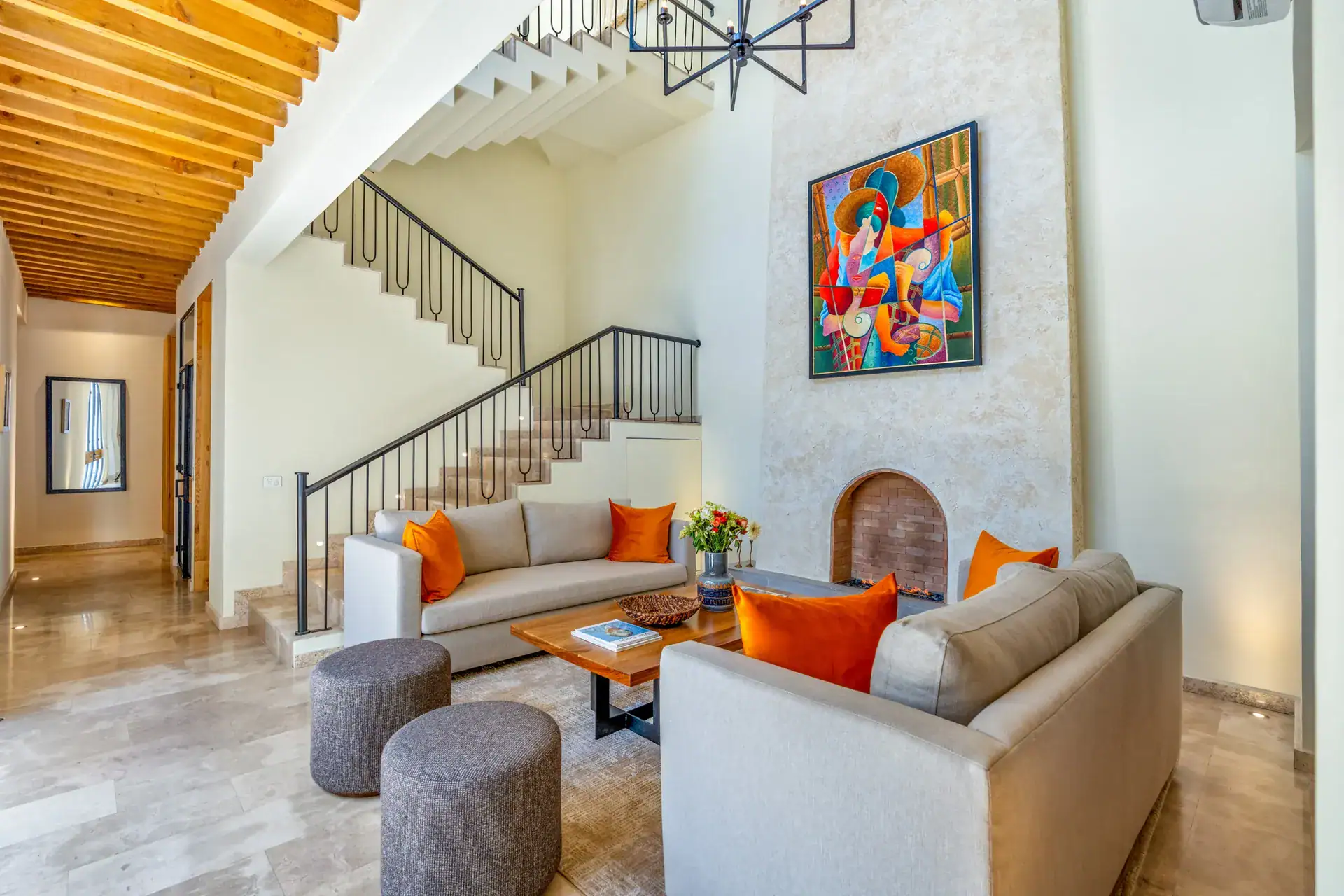 Casa Buenos Tiempos, living room with white sofas, orange cushions, a staircase and a colorful painting, San Miguel de Allende