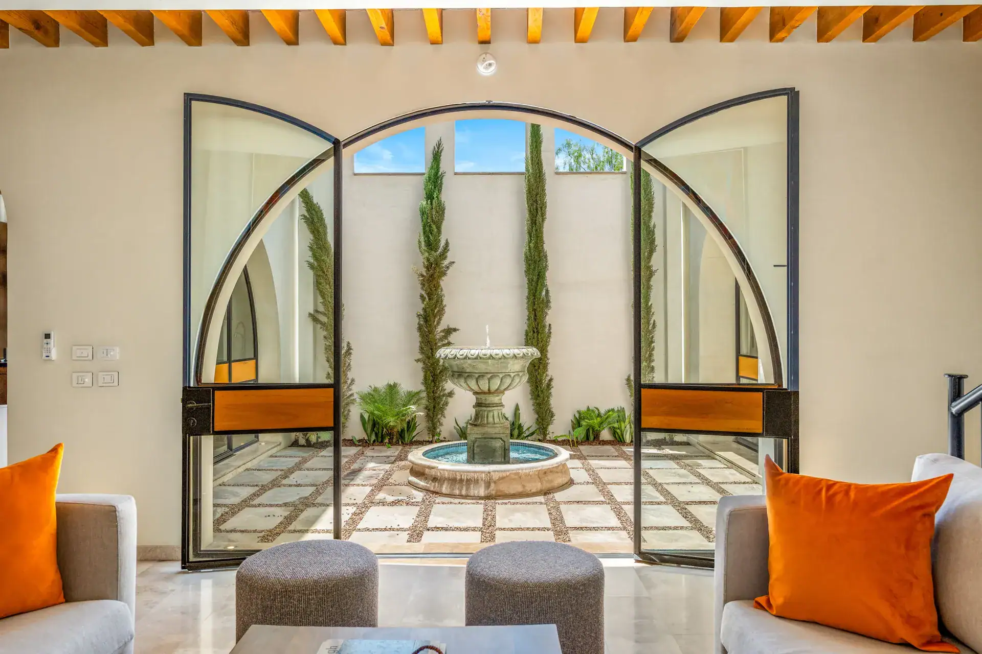 Casa Buenos Tiempos, arched steel doors framing a courtyard fountain and tall cypress trees, San Miguel de Allende