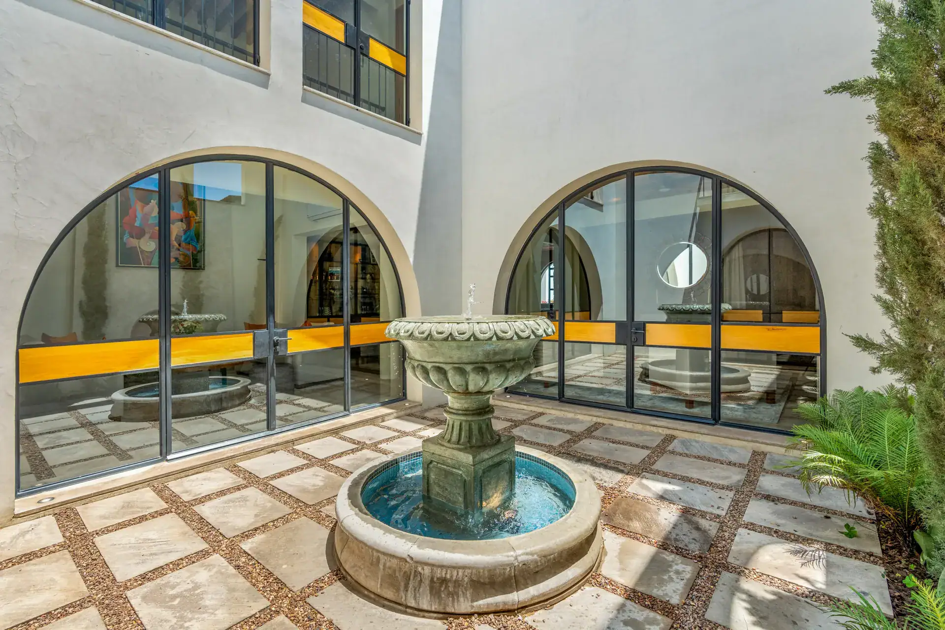 Casa Buenos Tiempos, courtyard with a stone fountain, patterned paving and arched windows, San Miguel de Allende