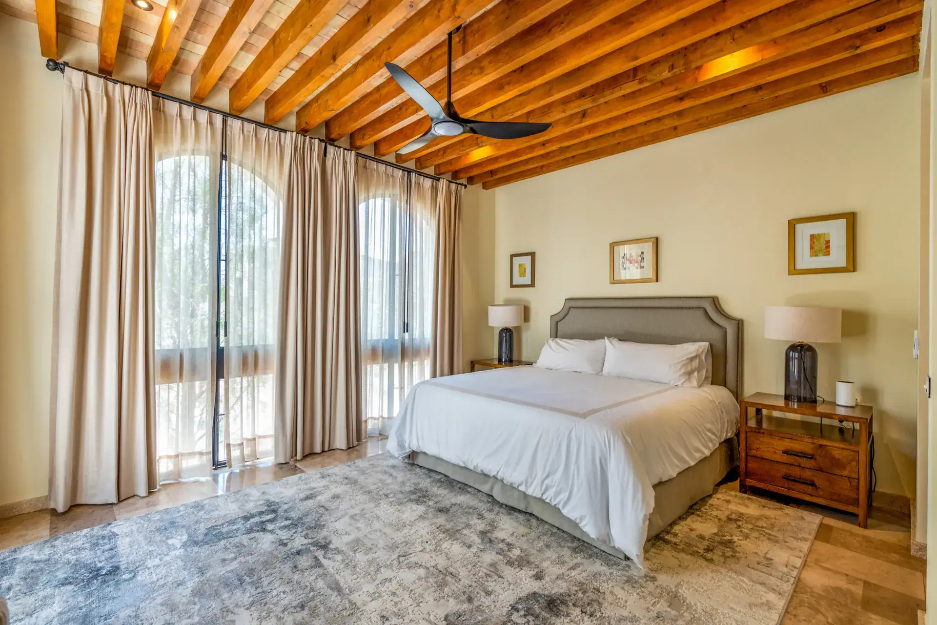 Casa Buenos Tiempos, bedroom with a gray headboard, white bedding, curtains and a wood-beam ceiling, San Miguel de Allende