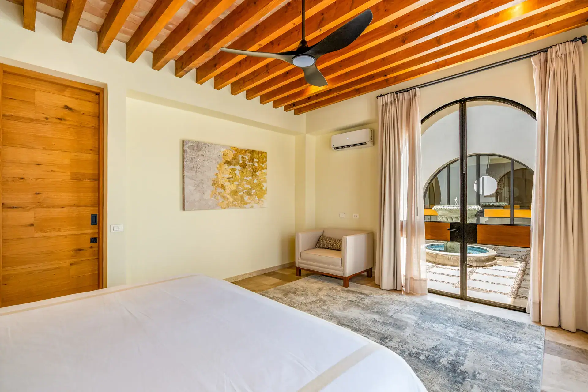 Casa Buenos Tiempos, bedroom with a view through an arched glass door to a courtyard fountain, San Miguel de Allende