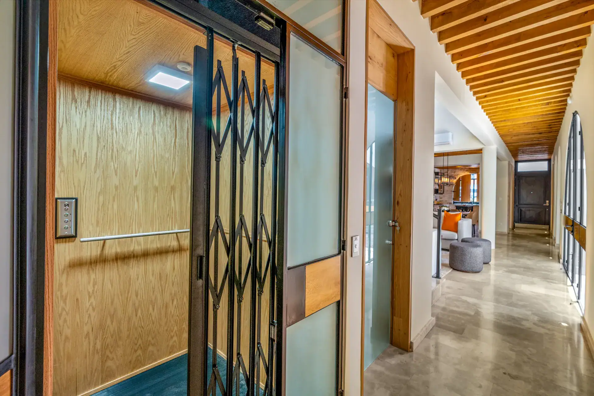 Casa Buenos Tiempos, corridor with a folding gate door, wood panels and a view down a long hall, San Miguel de Allende
