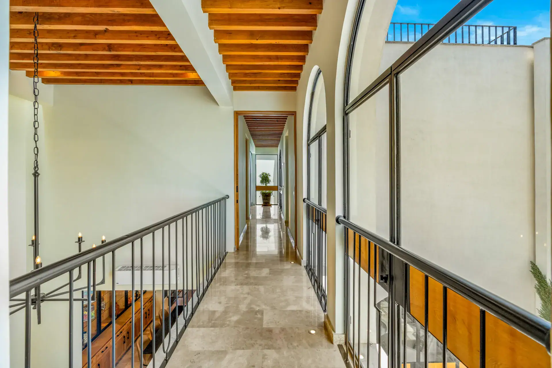 Casa Buenos Tiempos, upper gallery with an iron railing and a long hallway under wood beams, San Miguel de Allende