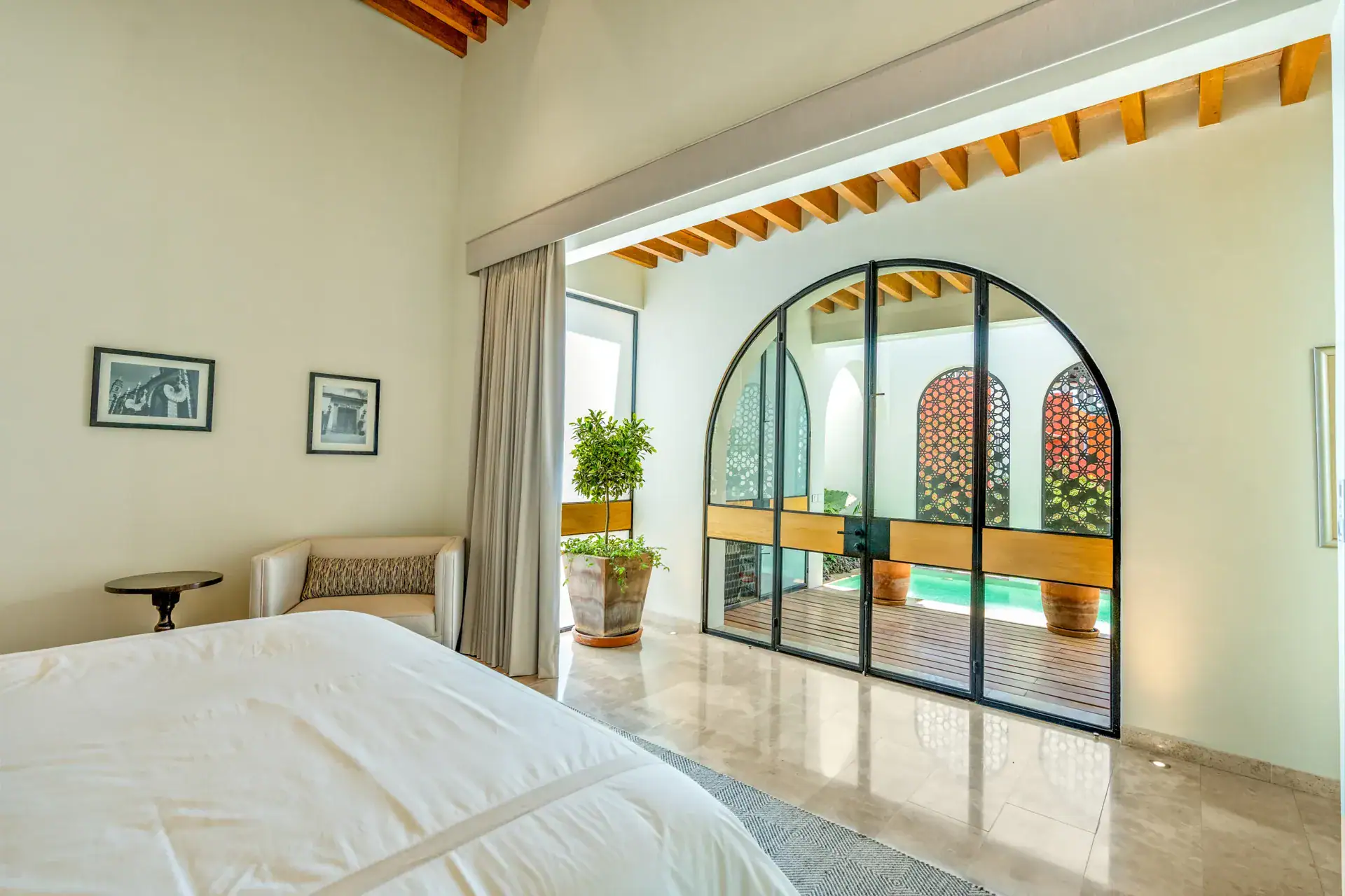 Casa Buenos Tiempos, bedroom with a white bed and arched glass doors to a pool patio, San Miguel de Allende