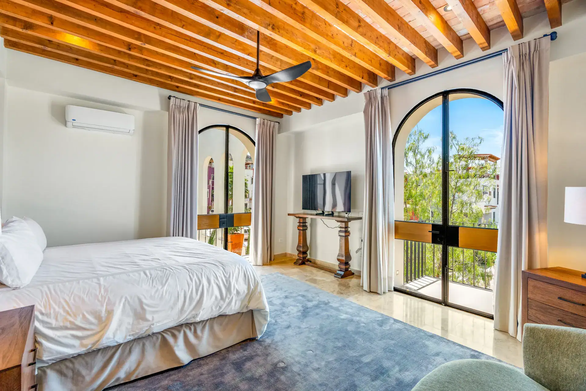 Casa Buenos Tiempos, bedroom with arched glass doors to a balcony, a television and a gray rug, San Miguel de Allende