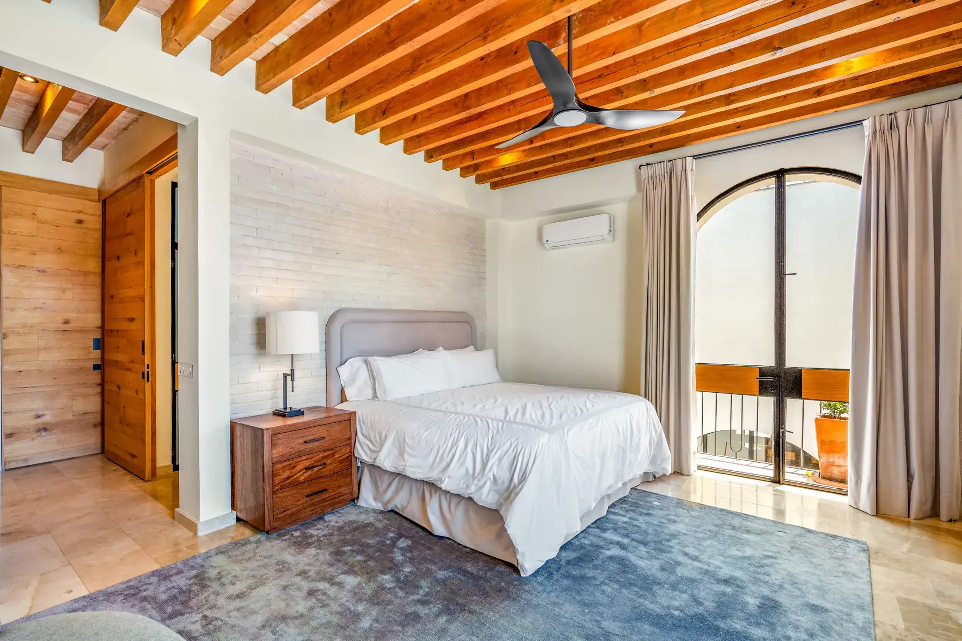 Casa Buenos Tiempos, bedroom with a gray headboard, white bedding and arched glass doors to a balcony, San Miguel de Allende