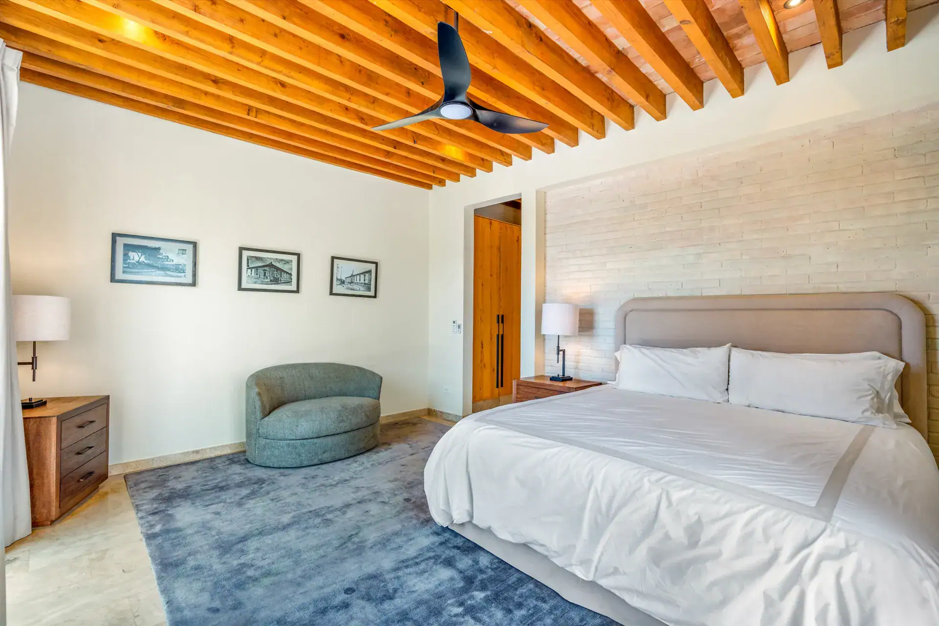 Casa Buenos Tiempos, bedroom with a ceiling fan, framed prints and a teal armchair, San Miguel de Allende