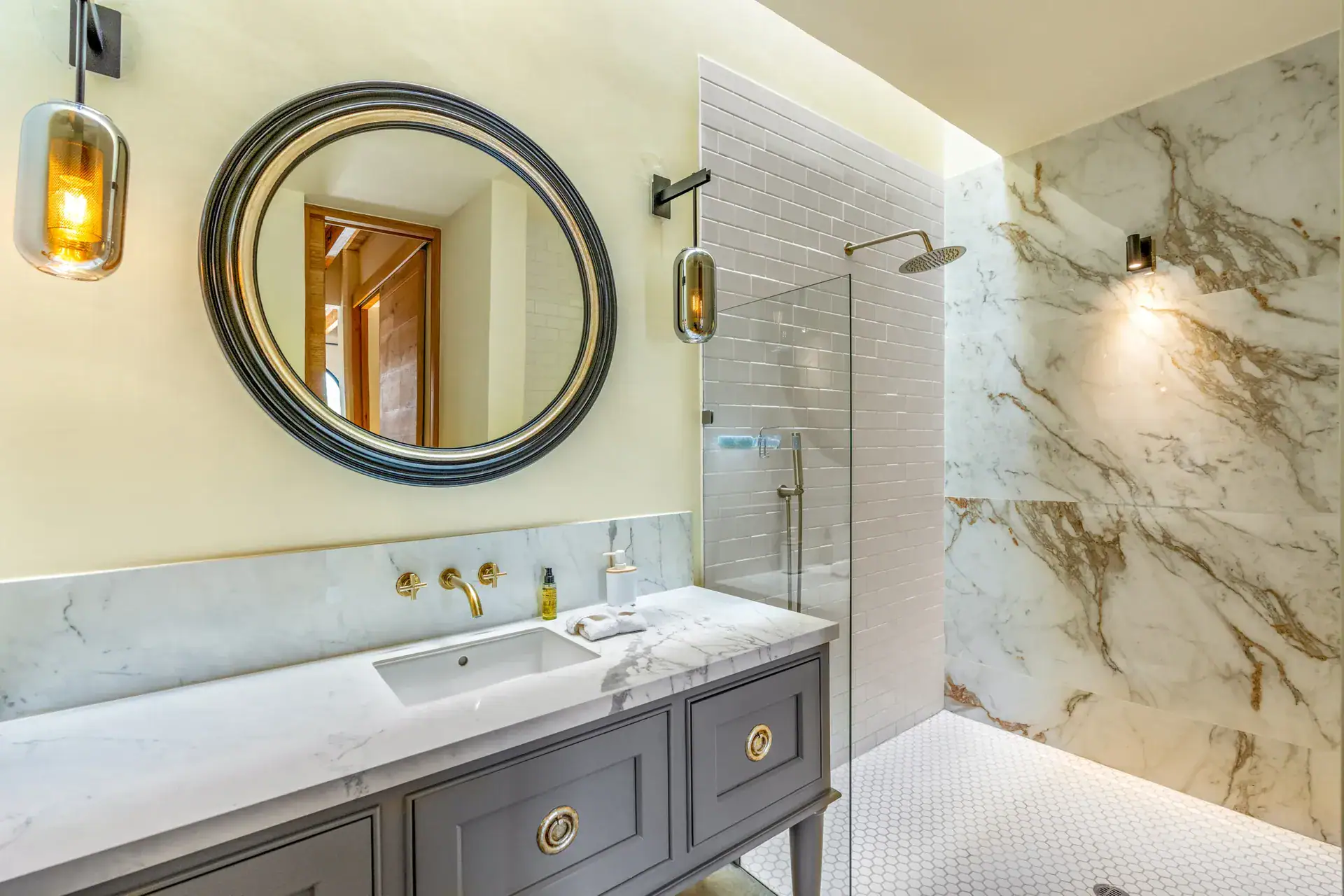 Casa Buenos Tiempos, bathroom with a round black-framed mirror, a marble-look shower and a gray vanity, San Miguel de Allende