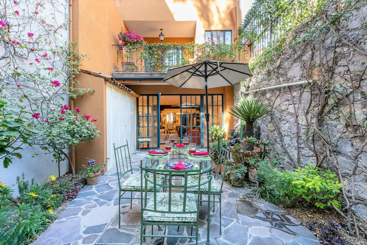 Casa Caminando, flagstone courtyard with an umbrella and flowering plants, San Miguel de Allende