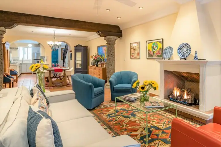Casa Caminando, living room with a fireplace, blue armchairs and a beamed ceiling, San Miguel de Allende