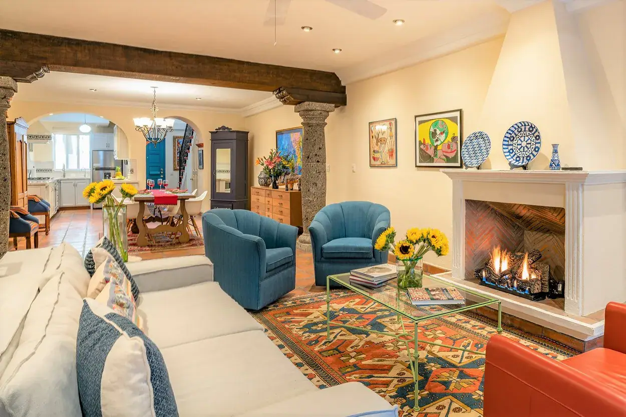Casa Caminando, living room with a fireplace, blue armchairs and a beamed ceiling, San Miguel de Allende