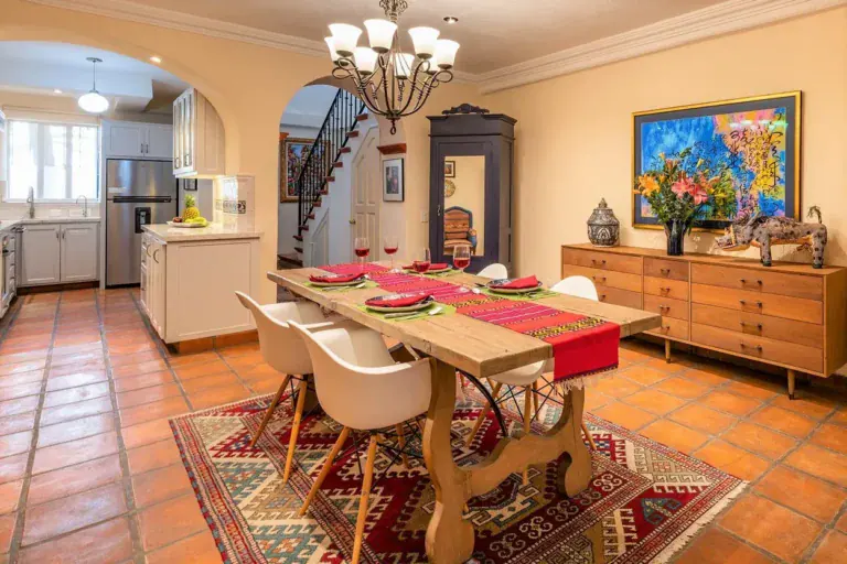 Casa Caminando, dining room with a wood table, white chairs and a chandelier, San Miguel de Allende