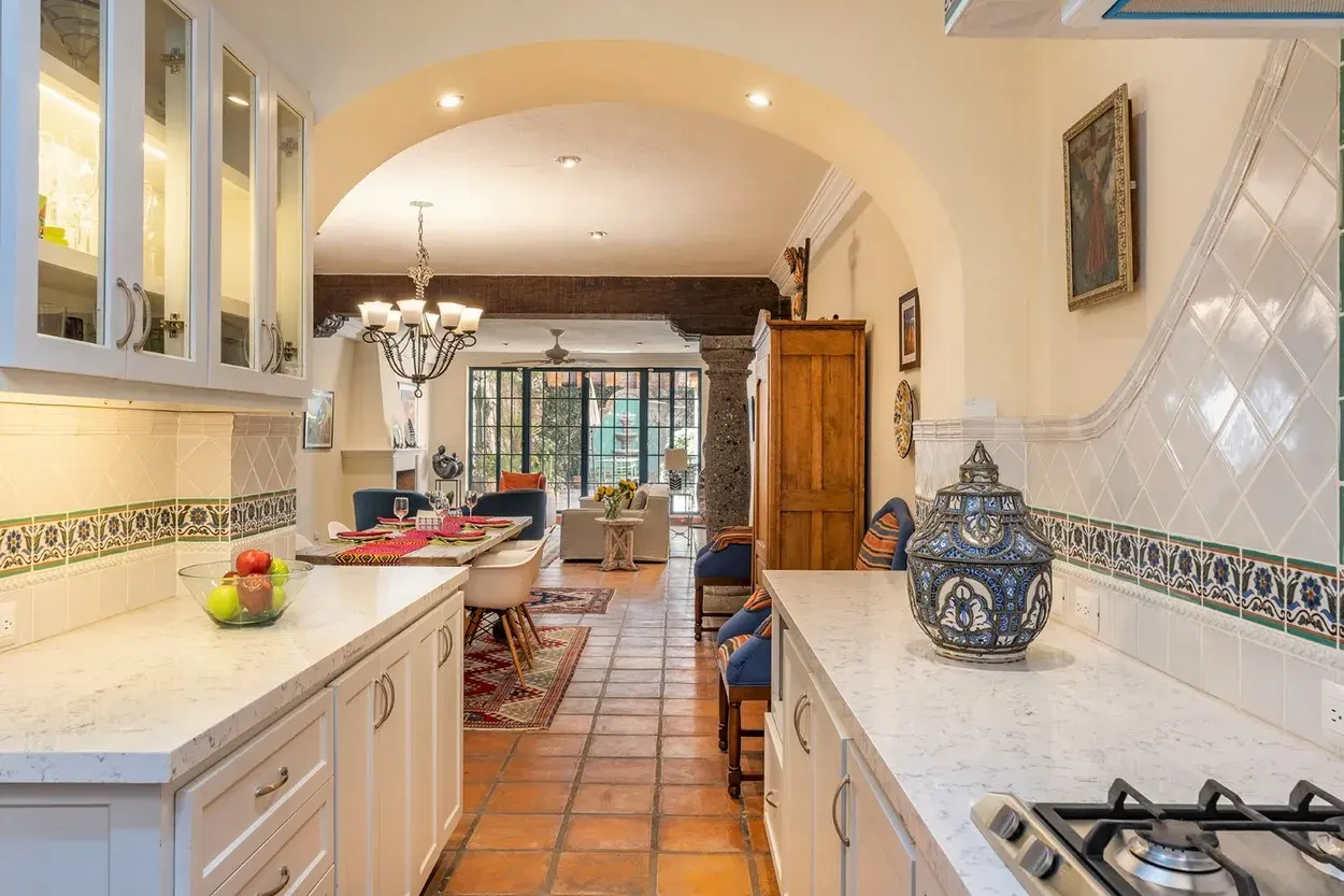 Casa Caminando, kitchen with white cabinets, talavera tile and an arched opening, San Miguel de Allende