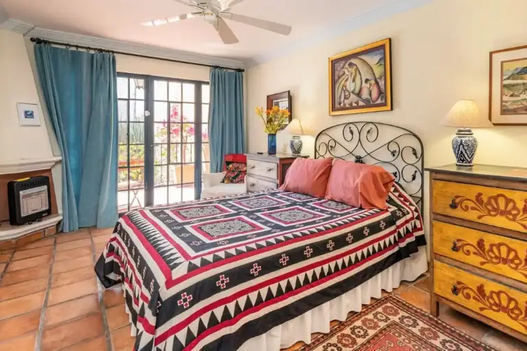 Casa Caminando, bedroom with a wrought-iron bed and a red and black bedspread, San Miguel de Allende