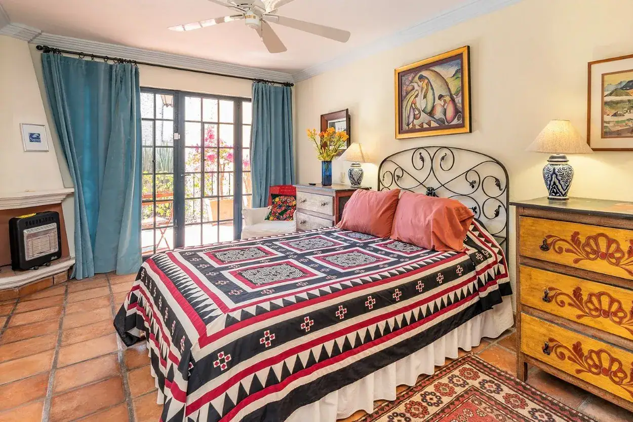 Casa Caminando, bedroom with a wrought-iron bed and a red and black bedspread, San Miguel de Allende