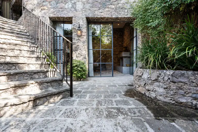 Casa Cañadita, stone courtyard with an iron stair rail and glass doors, San Miguel de Allende