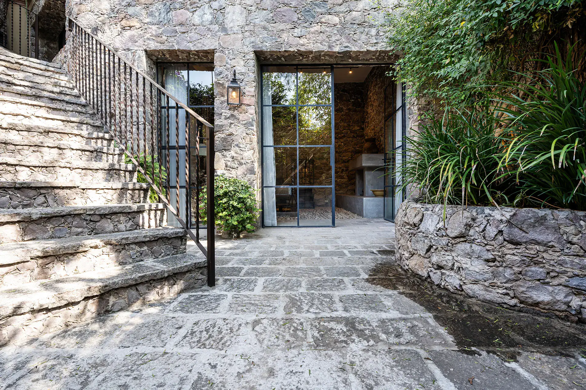 Casa Cañadita, stone courtyard with an iron stair rail and glass doors, San Miguel de Allende