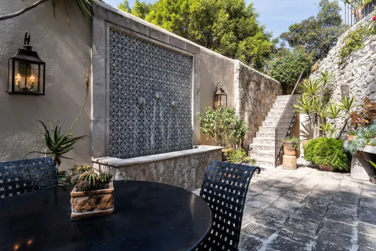Casa Cañadita, stone courtyard with a blue tile fountain wall and a dining table, San Miguel de Allende