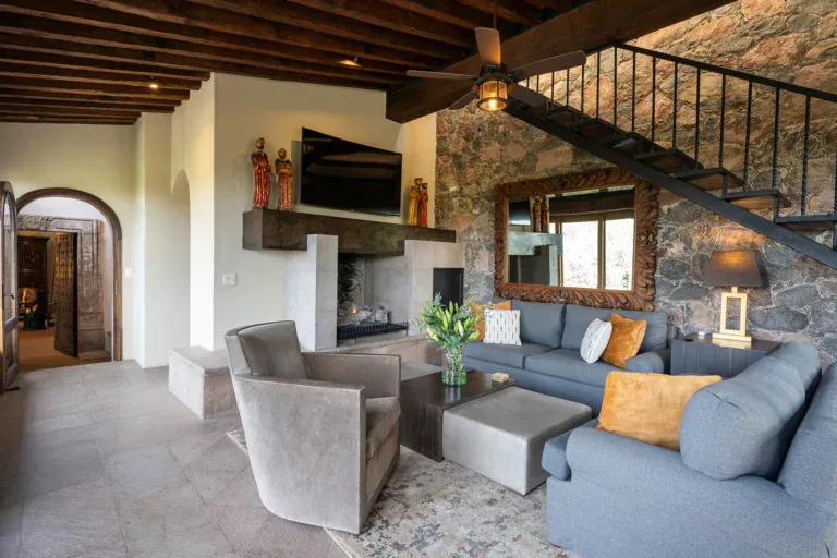 Casa Cañadita, living room with a stone wall, fireplace and gray sectional, San Miguel de Allende