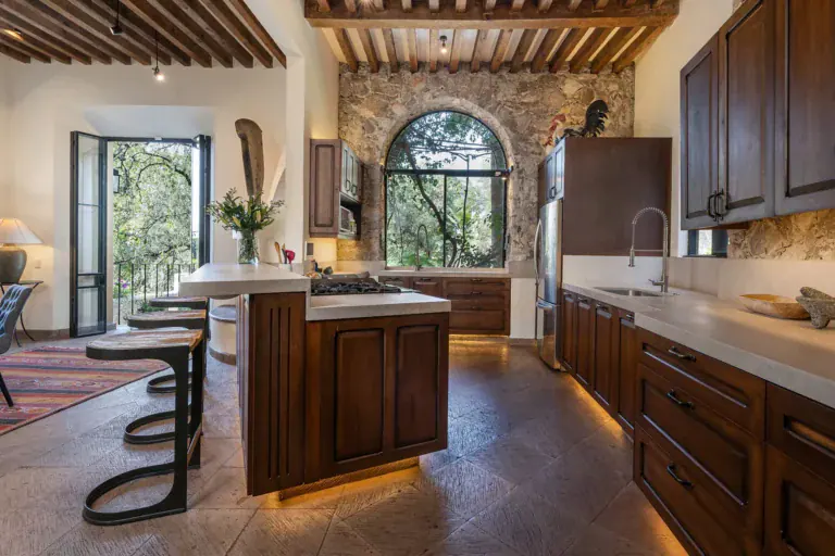 Casa Cañadita, kitchen with an island, bar stools and an arched stone window, San Miguel de Allende